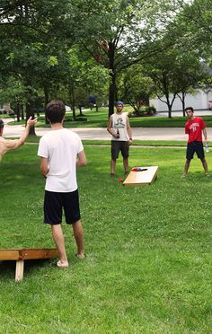 several men playing frisbee in the park on a sunny day with trees and grass