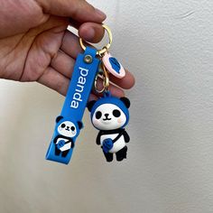 a hand holding a blue key chain with a panda on it's side and an id tag attached to it