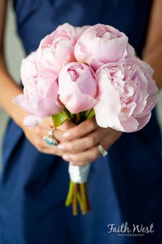 a woman in a blue dress holding a bouquet of pink flowers