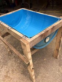 a blue pool sitting on top of a wooden table in the middle of a garage