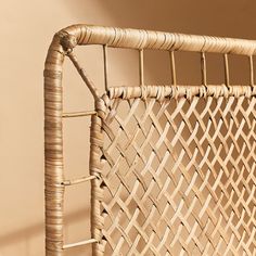 a wicker bed frame with no mattress on it, in front of a beige wall