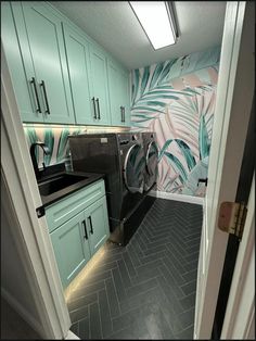 a washer and dryer in a small room with green cupboards on the wall