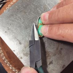 a person using a pair of scissors to cut something with green and white paint on it