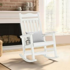 a white rocking chair sitting in front of a fireplace