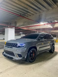 a grey jeep parked in a parking garage with red and white lines on the ceiling