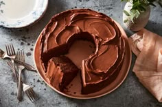 a chocolate cake with frosting on a plate next to silverware and utensils