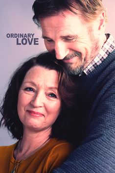 a man and woman hugging each other in front of a white wall with the words ordinary love on it