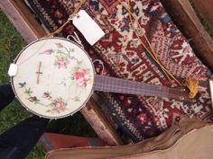 a close up of a musical instrument on the ground near rugs and other items