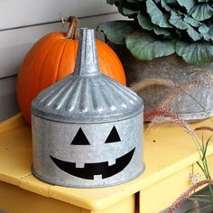 a metal container with a jack - o'- lantern face on it sitting next to a potted plant