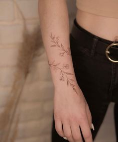 a woman's hand with a flower tattoo on her left wrist and the other arm