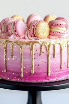 a pink and gold cake with macaroons on top