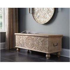 a wooden chest sitting in front of a window next to a clock on the wall