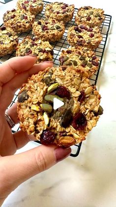 a person holding up a muffin on top of a cooling rack