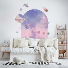 a room with a bed, rug and wall mural on the wall that has planets in it