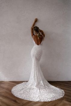 a woman in a white dress standing on a wooden floor with her back to the camera