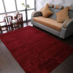 a living room area with a couch, chair and red rug on the hardwood floor