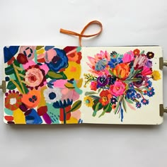 an open notebook with colorful flowers on it and a string attached to the front cover