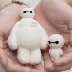 a person holding two small white stuffed animals in their hands with chains on the wrist