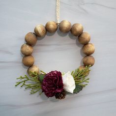 a wooden bead wreath with flowers and pinecone balls hanging on a wall