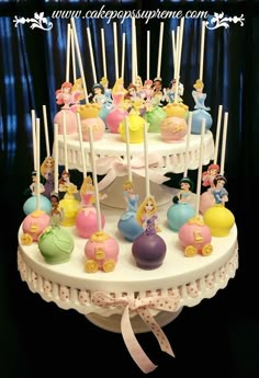 there is a cake that has many little princess cakes on it and candles in the shape of cupcakes