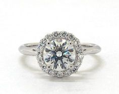 a white gold ring with an oval cut diamond surrounded by round diamonds