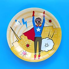 a paper plate with an image of a man in a blue shirt and red cape on it