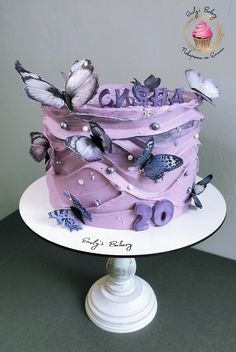 a purple cake with butterflies on it sitting on top of a table