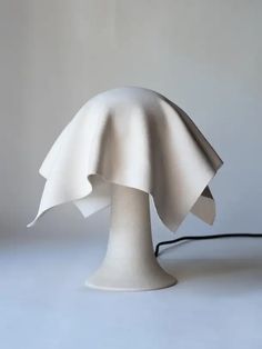 a white lamp sitting on top of a table next to a black cord in front of it