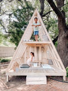 two children standing on top of a wooden structure in the middle of a yard with trees