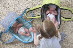 two babies are sitting in baby bouncers on the floor and one is holding a doll