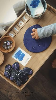 a child's hand is on the top of a wooden tray