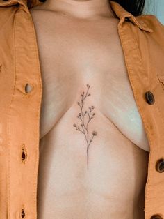 a woman's breast with a small flower tattoo on her left side ribcage