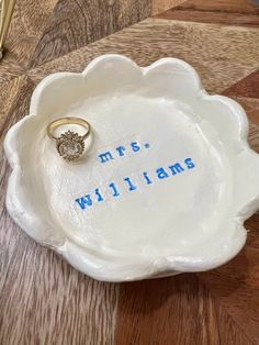 a ring dish with the words mrs williams written on it and a gold wedding band