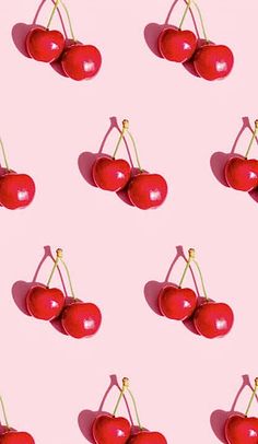 several cherries are shown on a pink background