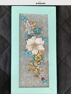 a blue frame with some flowers in it on a black surface and a gray background