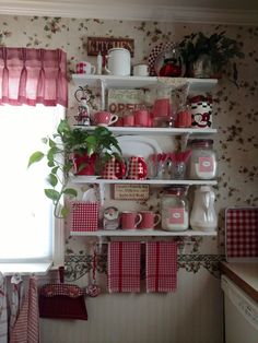 a kitchen with red and white decor on the wall, dishes and utensils