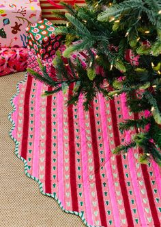 a christmas tree with presents under it on the floor next to a pile of wrapping paper