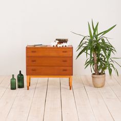 a wooden dresser sitting on top of a hard wood floor next to a potted plant