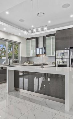 a large kitchen with marble counter tops and stainless steel appliances, along with lots of windows