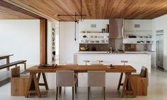 a kitchen with wooden ceiling and white counter tops next to a dining room table that has four chairs around it