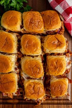 several sliders are arranged on a cutting board next to some parsley and red checkered napkin