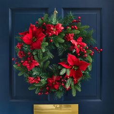 a christmas wreath with poinsettis and holly on a blue door