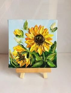 a painting of a sunflower on a wooden easel