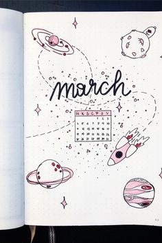 an open notebook with the words march written on it and various space related items around it