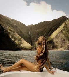 a beautiful woman sitting on top of a boat in the middle of a body of water