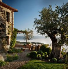 an outdoor dining area overlooking the water and mountains is shown in this photo, with stone benches on either side of the patio