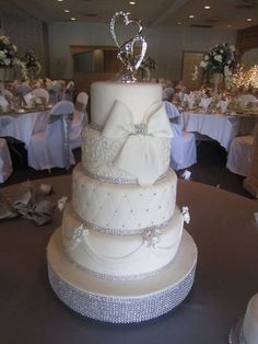 a wedding cake sitting on top of a table covered in white cloths and bows