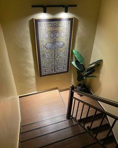 a painting hanging on the wall next to a stair case with a plant in it