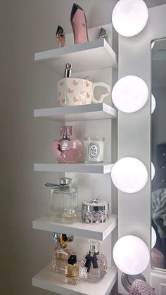 a white shelf filled with lots of bottles and other items next to a large mirror