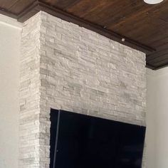 a flat screen tv mounted to the side of a brick wall in a living room